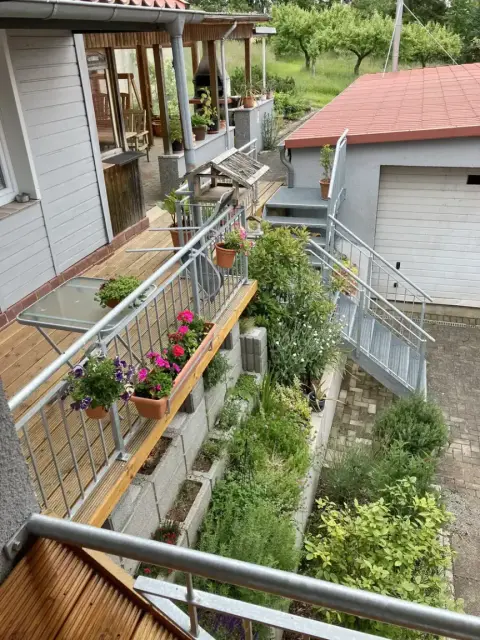 Blick vom Balkon auf Terrasse und Kräuterbeet