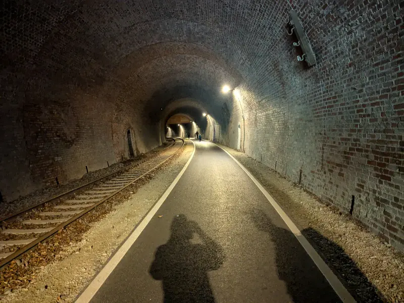 Beleuchteter Bahntunnel mit alten Gleisen und Radweg – Draisinen-Strecke im Eichsfeld