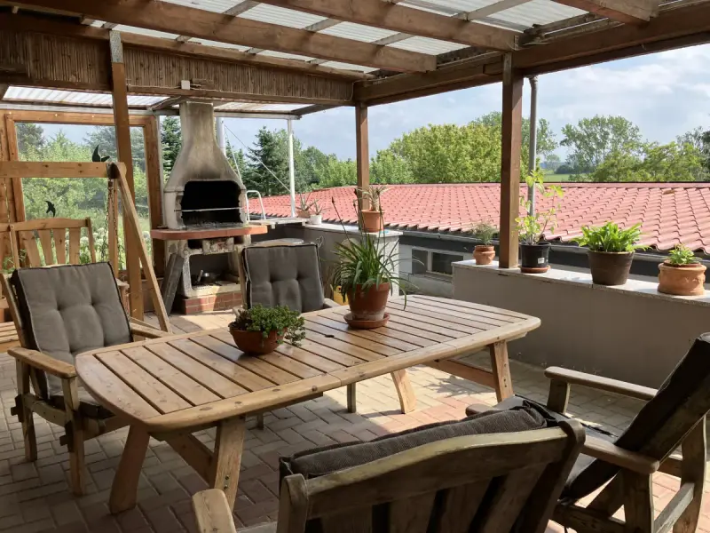 Überdachte Terrasse mit Grill und Sitzgruppe