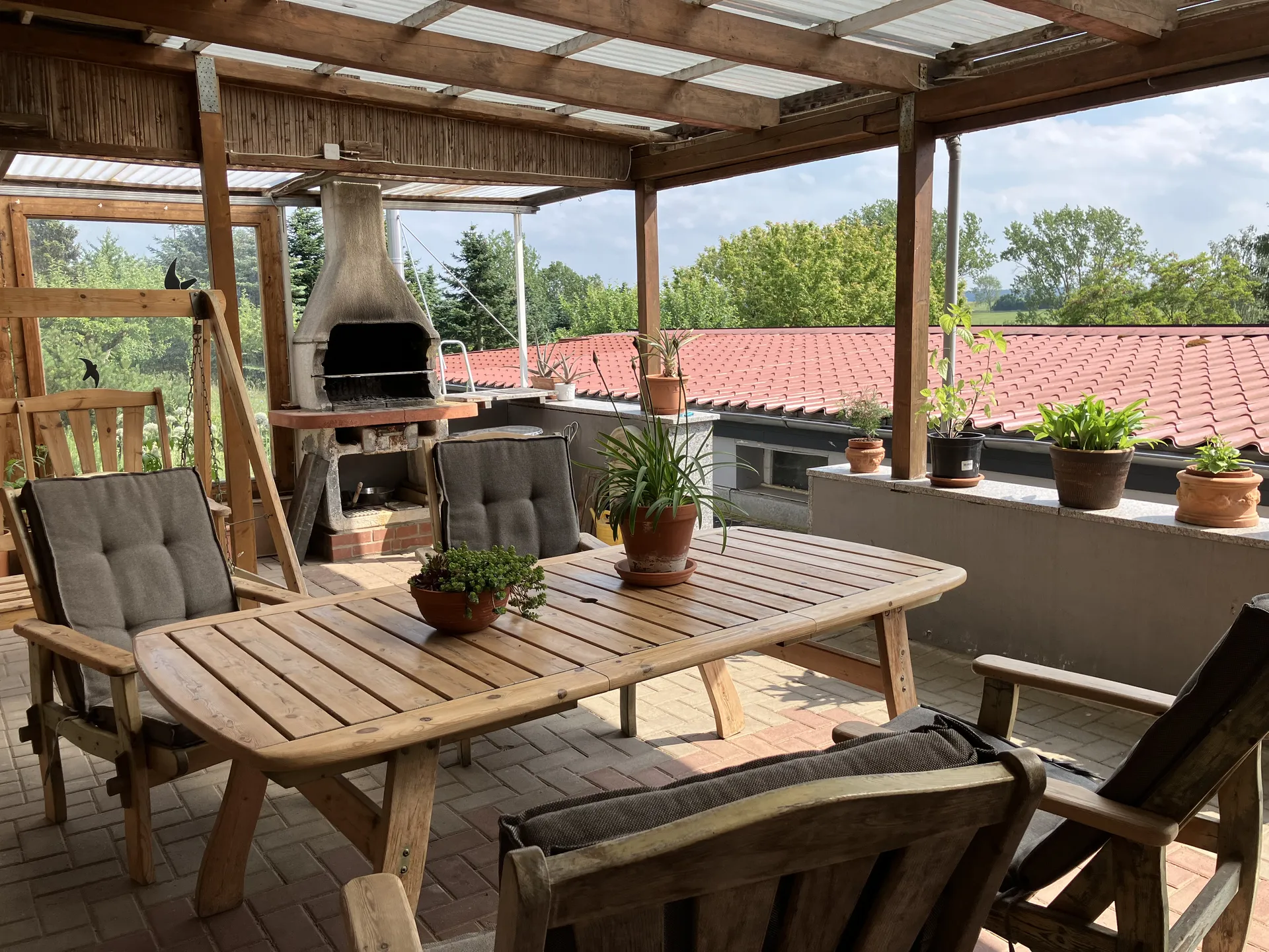 Überdachte Terrasse mit Grill und Sitzgruppe