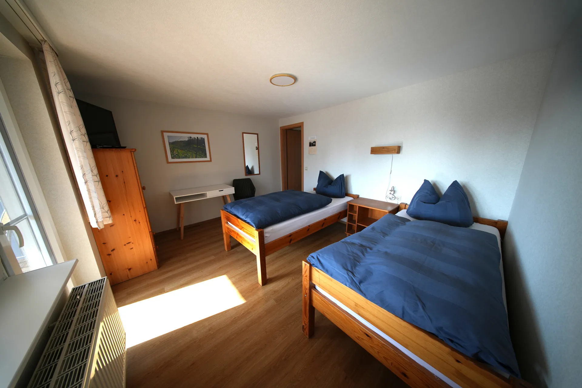 Balcony Room – Two single beds with wooden furniture and sunlight